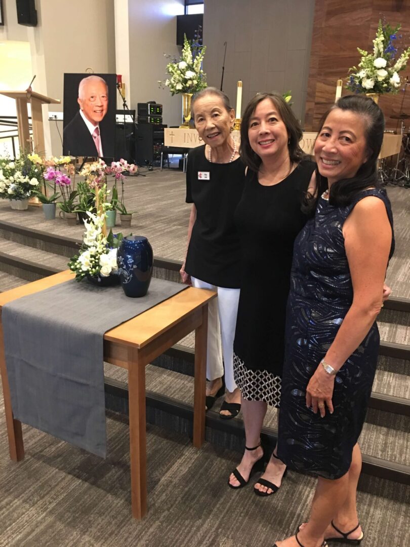 Three women taking a picture near an altar at a funeral