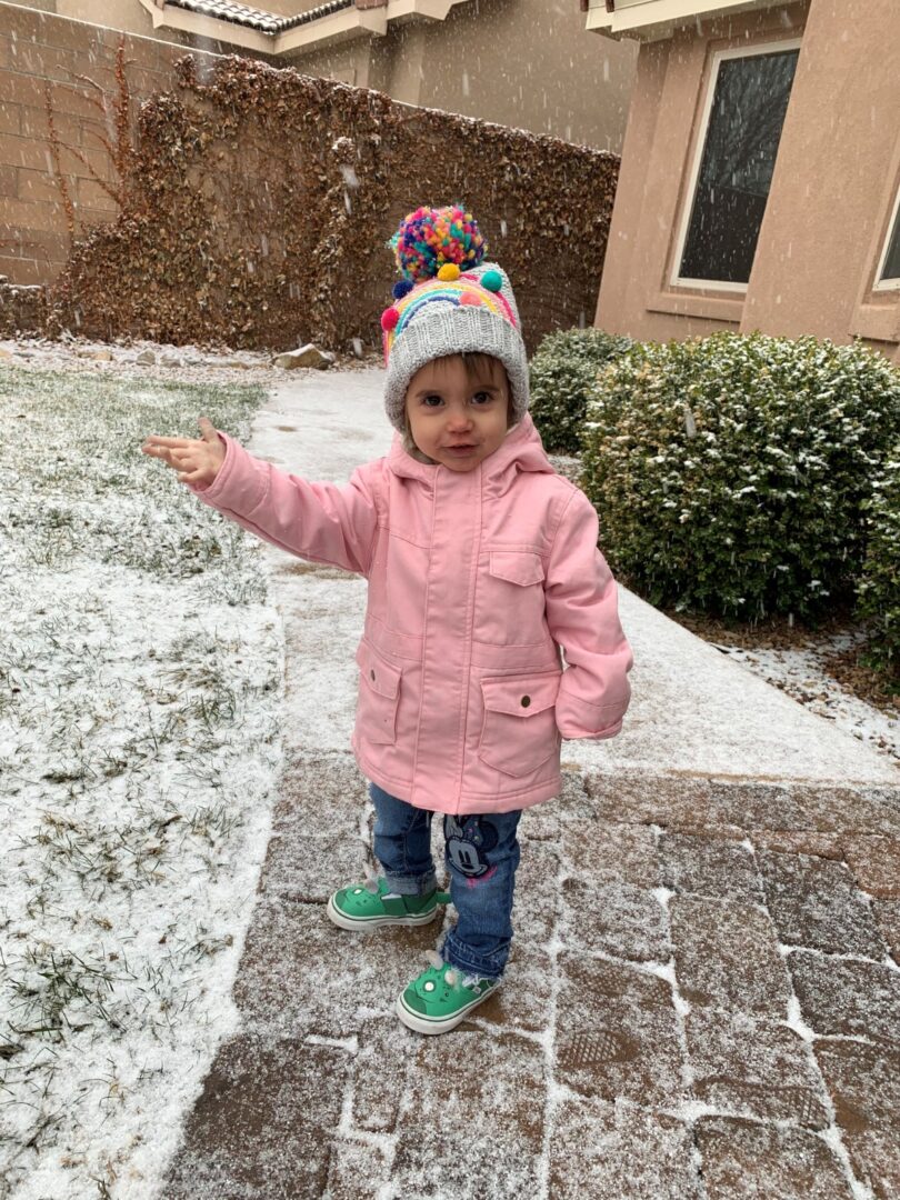 A little girl posing with snow falling in the background